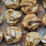 apple cider puffs resting on a cooling rack with wooden background