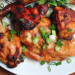 gochujang rubbed roast chien on a white plate with scallions