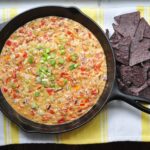 queso fundido in a cast iron pan with tortilla chips on the side