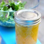 jar of triple citrus dressing with salad in background