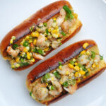 2 overstuffed hot dog rolls full of shrimp, corn and vegetables