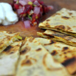 green chile and cheddar quesadillas cut into triangles and served with salsa and sour cream