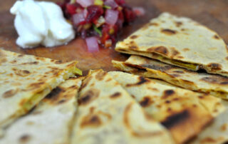 green chile and cheddar quesadillas cut into triangles and served with salsa and sour cream