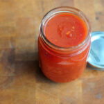 small jar of tomato sauce on wooden board
