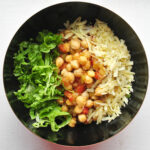 black bowl on white background full of chickpeas, cheese and lettuce taco bowl