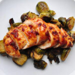chipotle honey chicken on a bed of brussels sprouts on a white plate