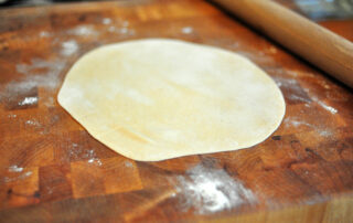 rolled out roti on a countertop with rolling pin in background