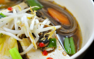 Tofu hot pot, bowl of noodles, tofu and vegetables in a warm ginger-garlic broth