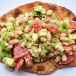naan bread piled high with avocado, white bean and grapefruit salad