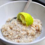 coconut lime oatmeal in a white bowl with a squeezed lime wedge on top