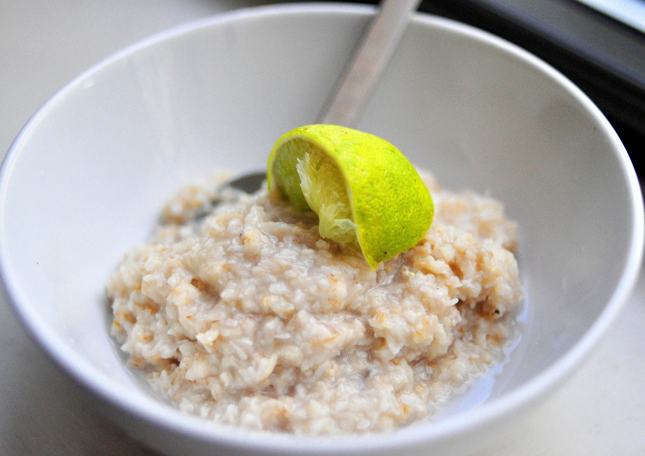 coconut lime oatmeal in a white bowl with a squeezed lime wedge on top