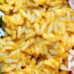 close up of rice with with green yellow and red vegetable mixed into it.