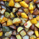an expanse of roasted vegetables including potatoes, swee potatoes, peppers and squash