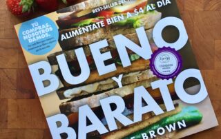 copy of Bueno Y Barato book with strawberries on a wood block background